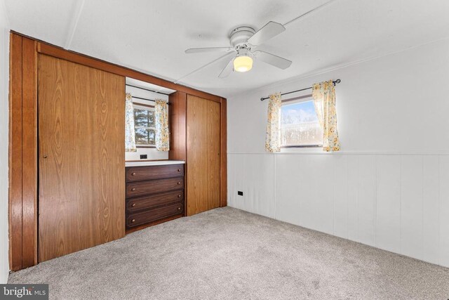 unfurnished bedroom featuring multiple windows, ceiling fan, and carpet