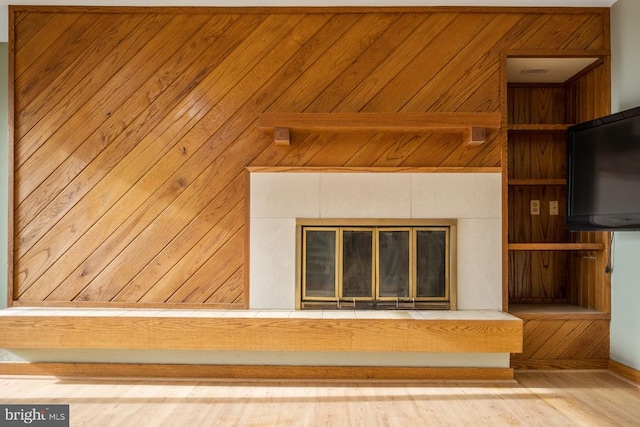 details featuring wood walls, a fireplace, and wood finished floors