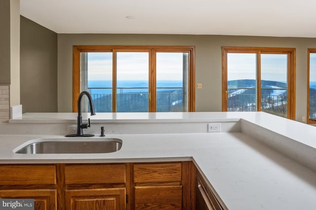 kitchen featuring light countertops, brown cabinetry, and a sink