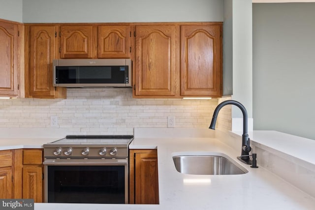 kitchen with light countertops, appliances with stainless steel finishes, backsplash, and a sink