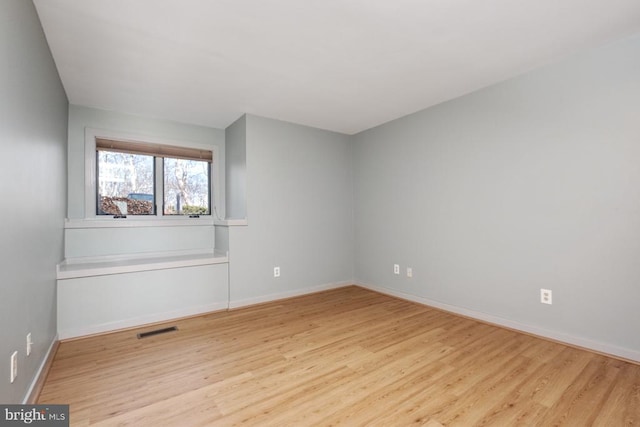 spare room featuring visible vents, baseboards, and wood finished floors