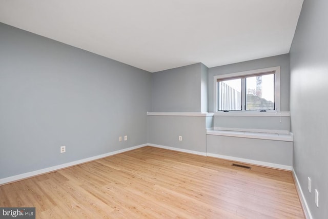 spare room featuring visible vents, baseboards, and wood finished floors