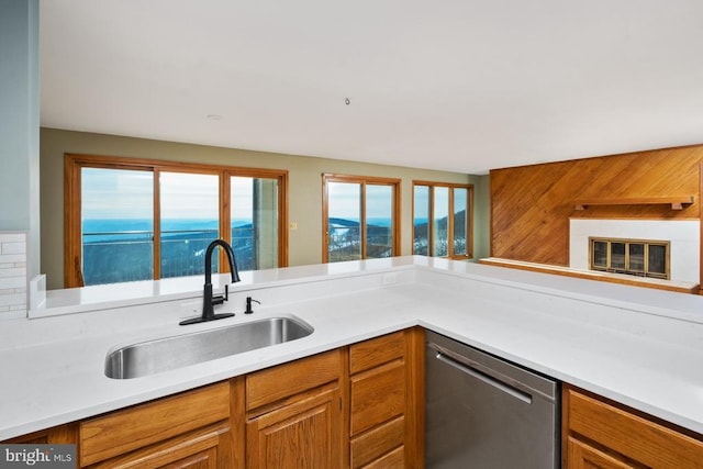 kitchen with brown cabinets, light countertops, a sink, and stainless steel dishwasher