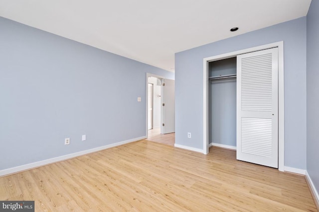 unfurnished bedroom with light wood finished floors, baseboards, and a closet