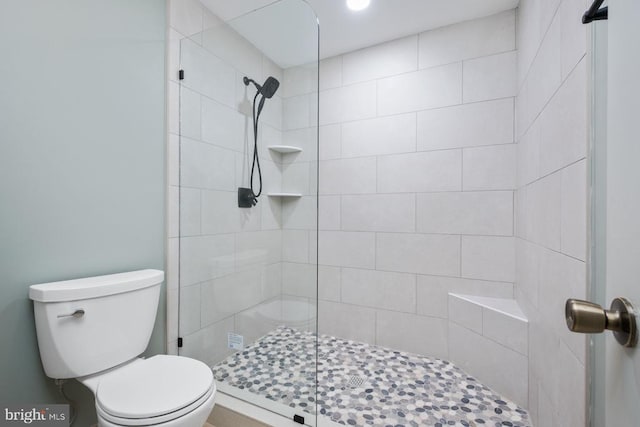 full bath with tiled shower and toilet