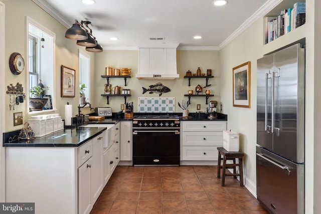 kitchen with dark countertops, high end appliances, open shelves, and white cabinetry