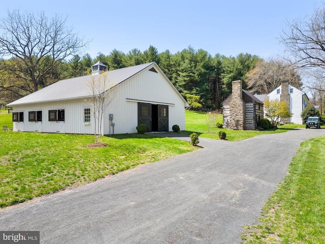 view of side of home with a lawn, an outdoor structure, and metal roof