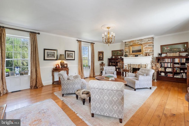 living area featuring hardwood / wood-style floors, ornamental molding, a healthy amount of sunlight, and an inviting chandelier