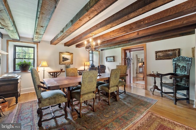 dining area with baseboards, wood finished floors, an inviting chandelier, and beam ceiling