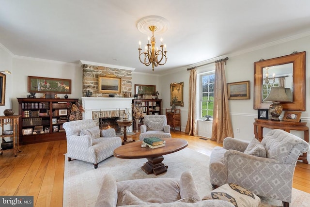 living room with a fireplace, a chandelier, crown molding, and light wood finished floors