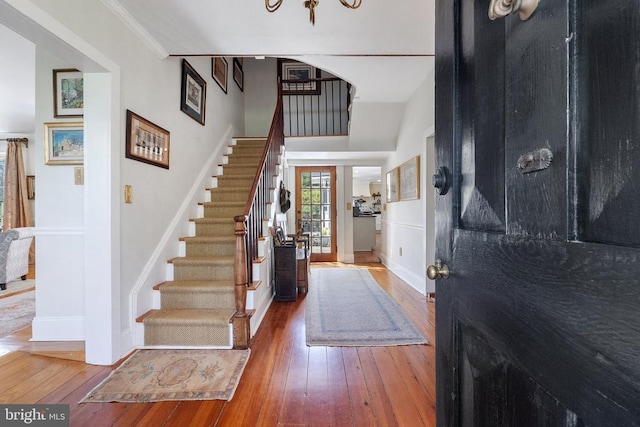 foyer with ornamental molding, hardwood / wood-style floors, stairway, and baseboards