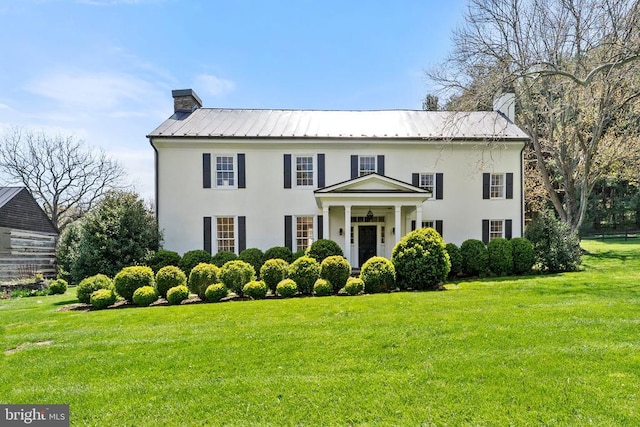 view of front facade featuring a chimney, a front lawn, and stucco siding