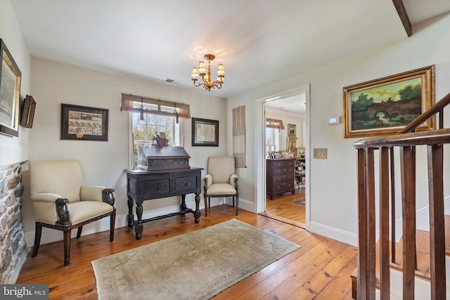 living area with visible vents, light wood-type flooring, a chandelier, and baseboards