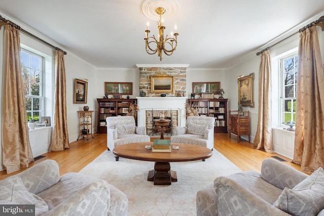 living area featuring light wood-style flooring, plenty of natural light, a notable chandelier, and crown molding