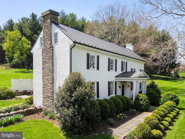 view of front of home with a chimney, a standing seam roof, and metal roof