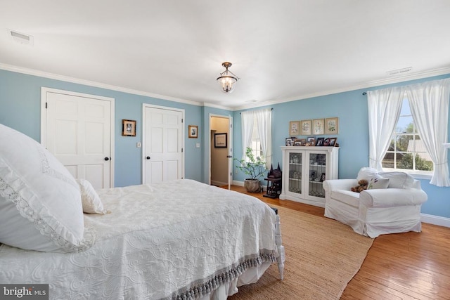 bedroom with wood finished floors, crown molding, and multiple windows