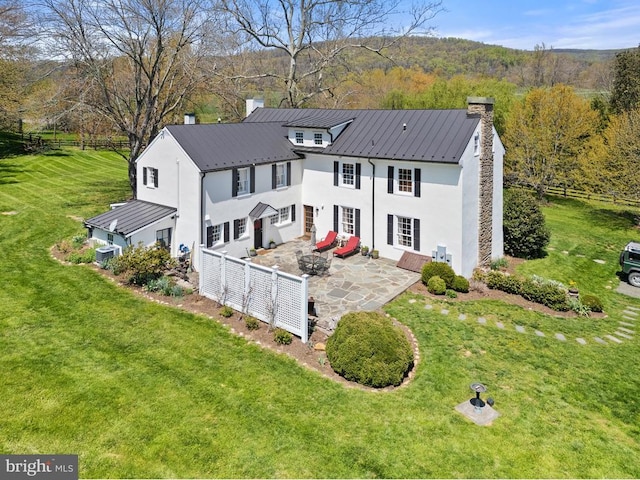 back of property featuring a patio area, a yard, a chimney, stucco siding, and fence