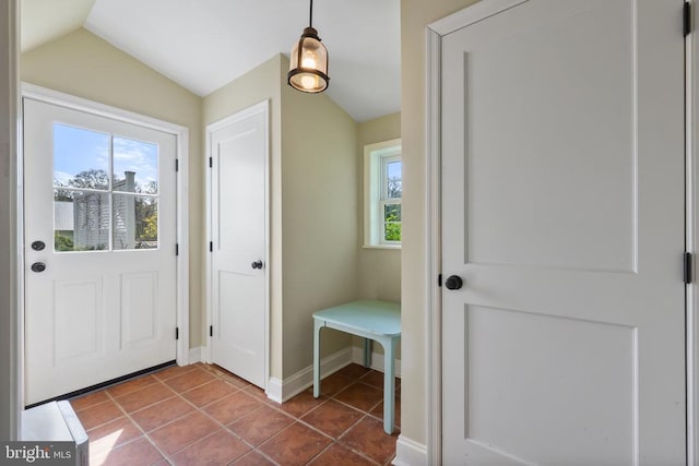interior space featuring a wealth of natural light, dark tile patterned floors, vaulted ceiling, and baseboards