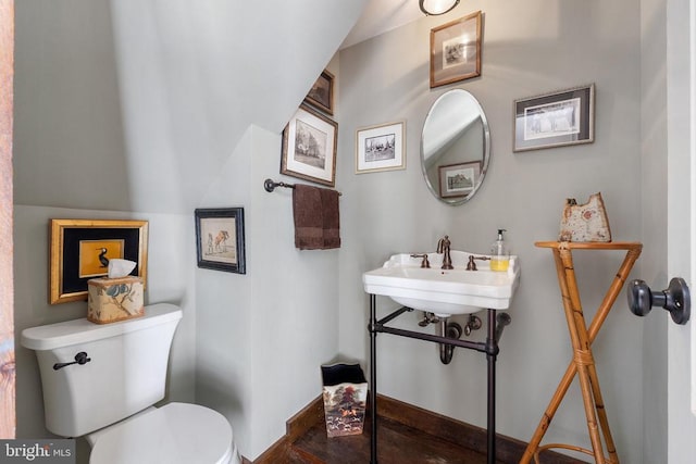 half bath featuring baseboards and toilet