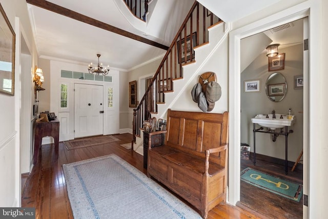 entrance foyer featuring an inviting chandelier, hardwood / wood-style floors, ornamental molding, baseboards, and stairway