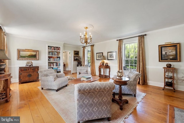 living room with an inviting chandelier, crown molding, light wood finished floors, and baseboards