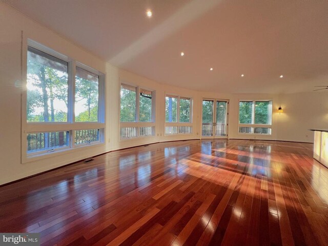 unfurnished living room featuring visible vents, hardwood / wood-style floors, and vaulted ceiling