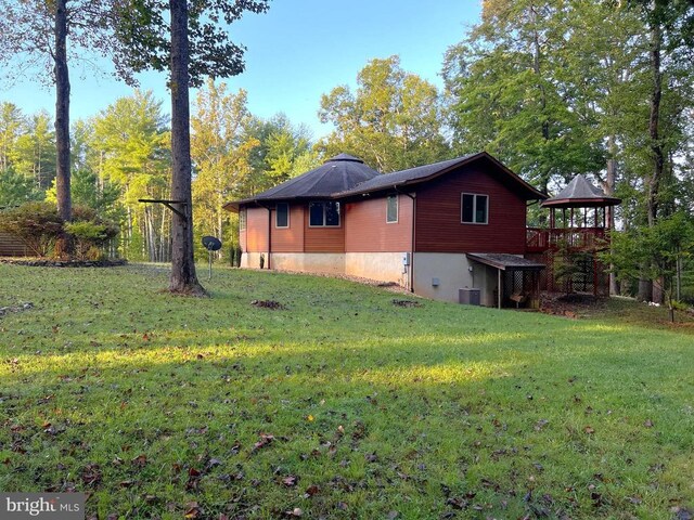 view of side of home with a gazebo, a lawn, and central AC