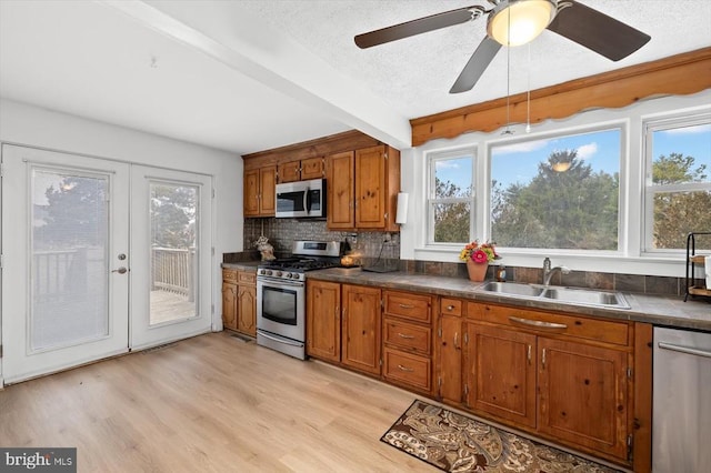 kitchen featuring a sink, light wood-style floors, appliances with stainless steel finishes, and brown cabinetry