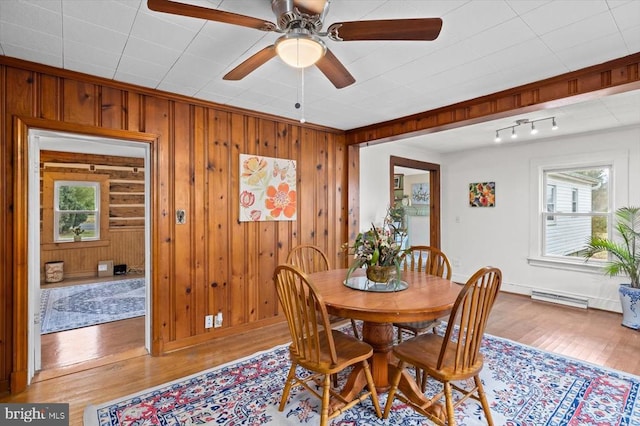 dining area with wood walls, a ceiling fan, and wood finished floors