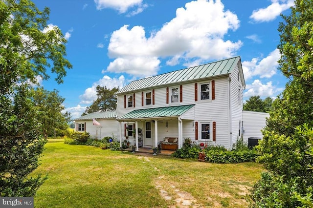 view of front facade featuring a standing seam roof, a front yard, covered porch, and metal roof