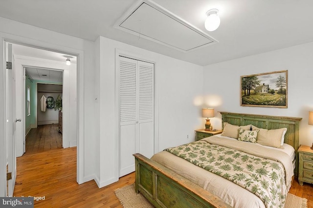 bedroom with a closet, light wood-style flooring, and attic access