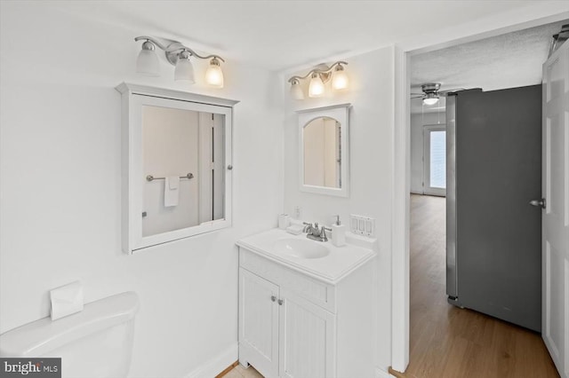 bathroom featuring toilet, vanity, a ceiling fan, and wood finished floors