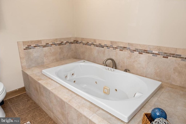 full bath featuring tile patterned floors, toilet, a tub with jets, and baseboards