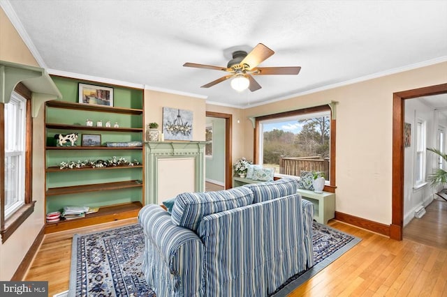 living area with a textured ceiling, a ceiling fan, light wood-type flooring, and ornamental molding