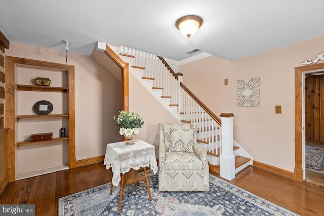 living area with visible vents, baseboards, built in features, stairs, and wood finished floors