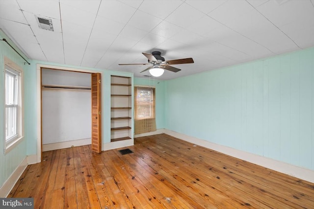 unfurnished bedroom featuring wood-type flooring, visible vents, a closet, and ceiling fan