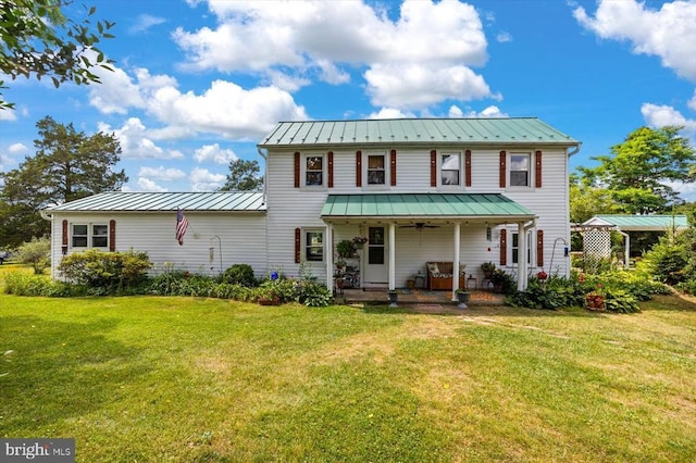 view of front of house with a standing seam roof, a front lawn, covered porch, and metal roof