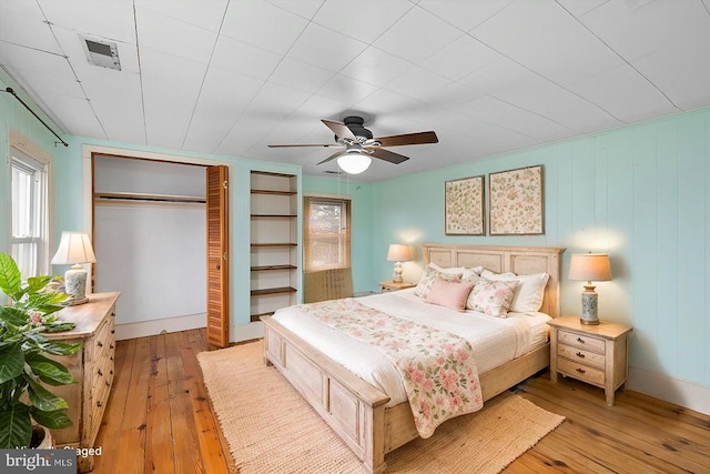 bedroom with a ceiling fan, visible vents, a closet, and light wood finished floors