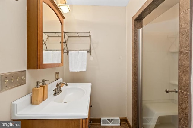 bathroom featuring visible vents, vanity, a shower, and baseboards