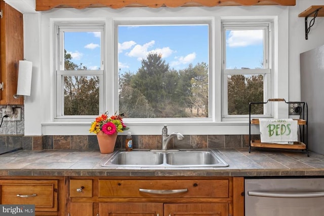 kitchen featuring dishwasher, brown cabinets, a wealth of natural light, and a sink