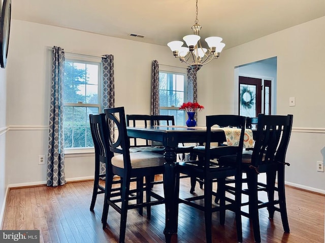 dining room with wood-type flooring, baseboards, a notable chandelier, and visible vents