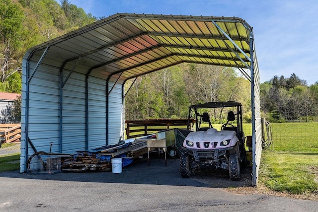 view of vehicle parking featuring a forest view and a carport