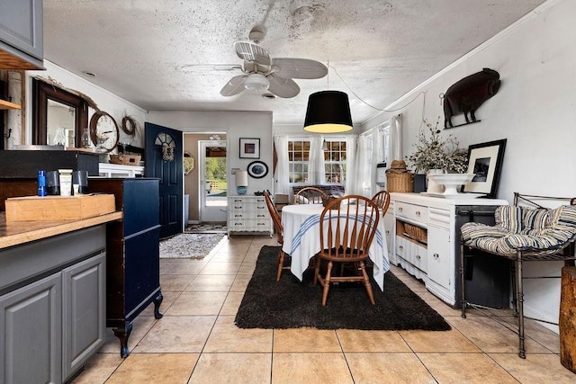 dining area with a ceiling fan, a textured ceiling, ornamental molding, and light tile patterned floors