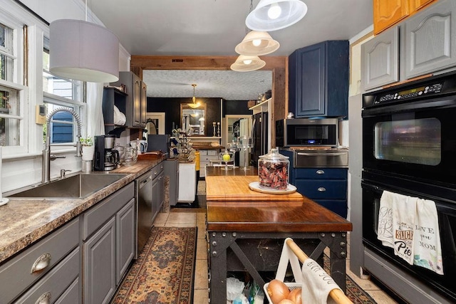 kitchen featuring appliances with stainless steel finishes, a sink, light tile patterned floors, pendant lighting, and a warming drawer
