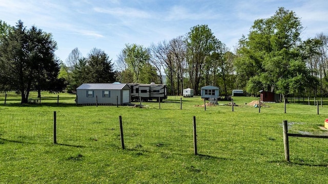 view of yard with fence, an outbuilding, and a shed