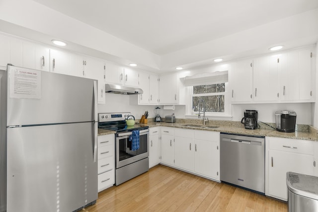 kitchen with sink, light stone counters, appliances with stainless steel finishes, light hardwood / wood-style floors, and white cabinets