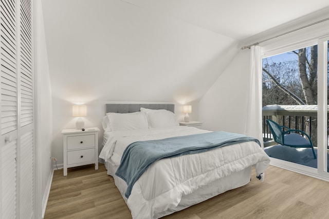 bedroom with light hardwood / wood-style flooring, access to outside, and lofted ceiling