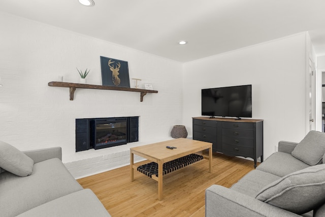 living room with a brick fireplace and wood-type flooring