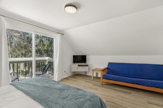 bedroom with wood-type flooring, vaulted ceiling, and access to exterior