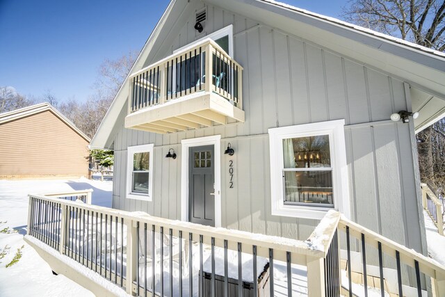 snow covered property entrance featuring a balcony